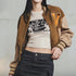 Person wearing a brown letterman jacket over a graphic t-shirt with text on a gray background